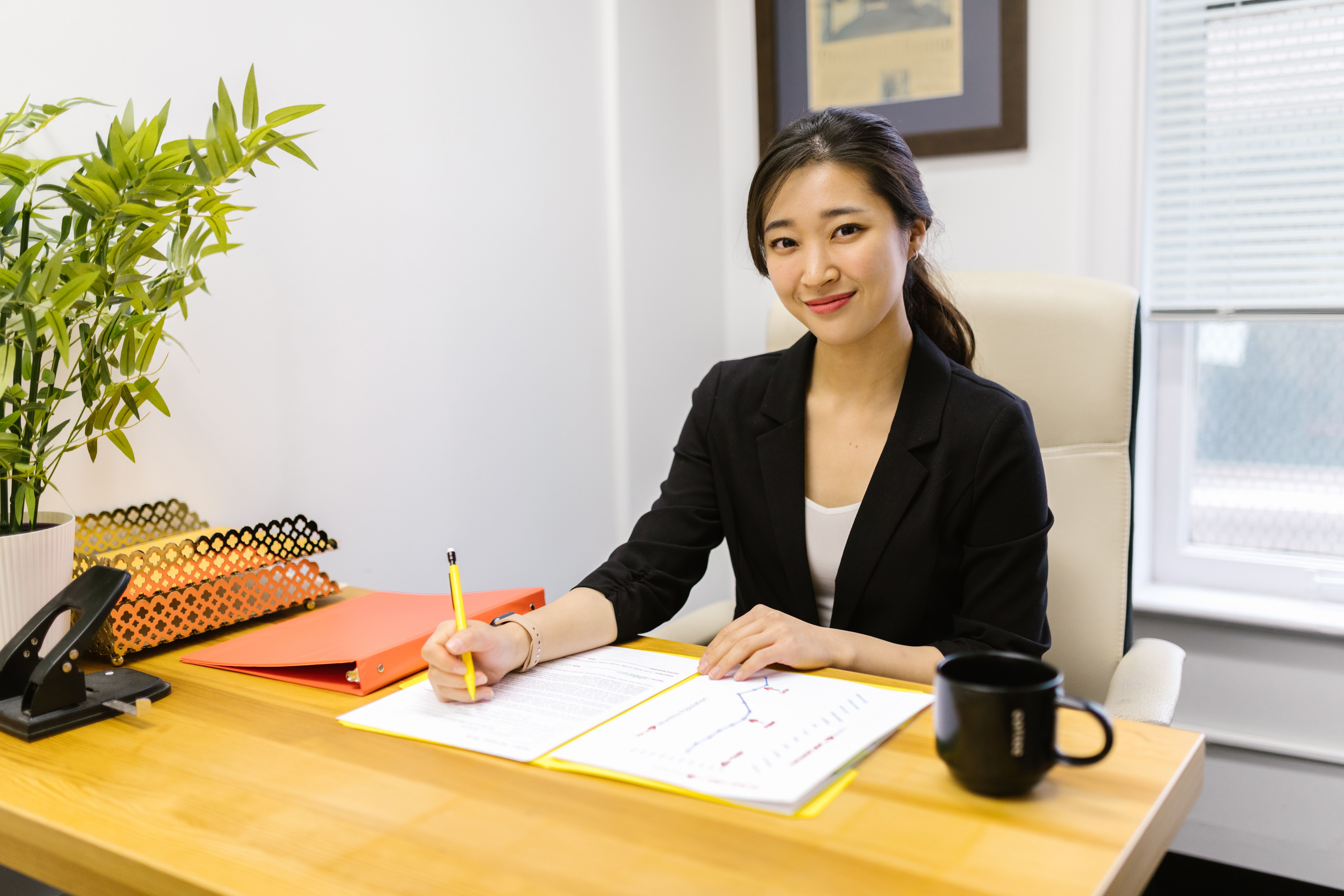 A professional woman sitting at a desk writing on documents