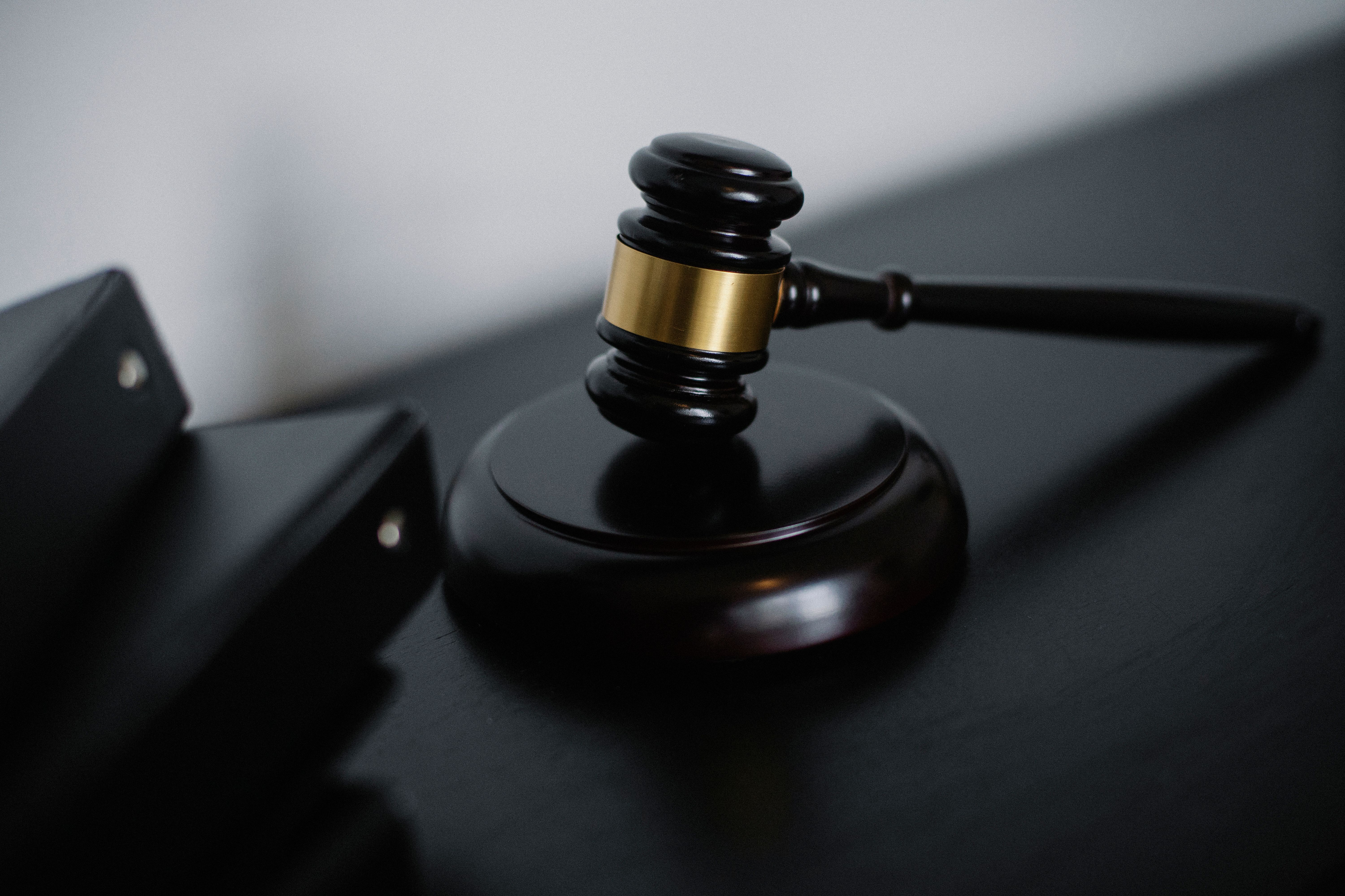 A wooden gavel resting on a dark surface next to a black binder