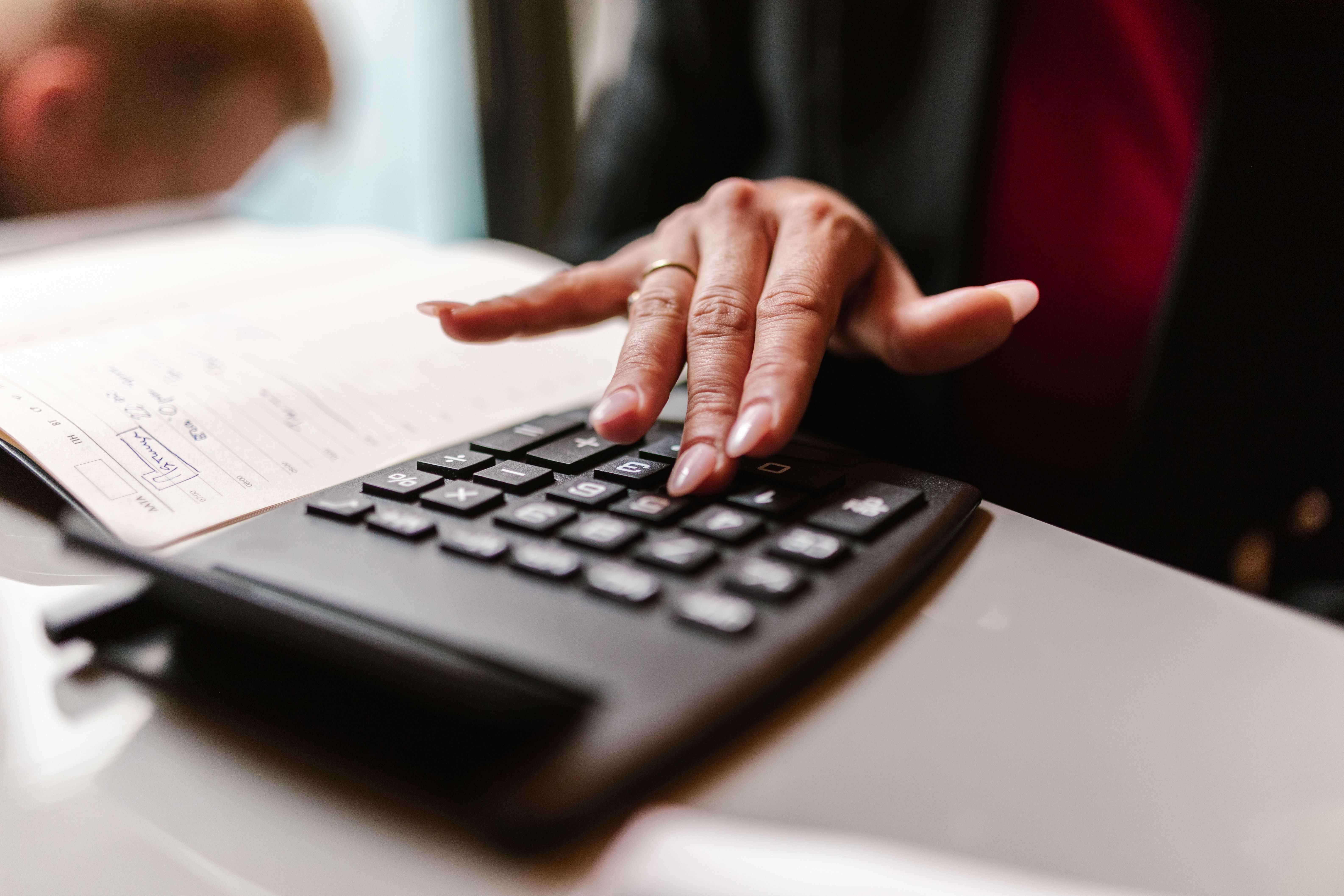 A hand using a calculator next to an open ledger